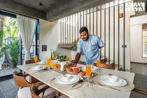 a man is standing at a table with a meal at StayVista at Arabella with Pool & Lawn in Colva +29 photos