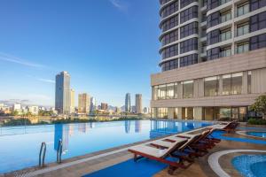 einen Pool mit einer Skyline der Stadt im Hintergrund in der Unterkunft Meliá Vinpearl Danang Riverfront in Đà Nẵng + 45 Fotos