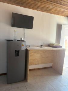een bureau met een koelkast en een televisie aan de muur bij CABAÑAS CAMPO y MAR in Playa Dorada
