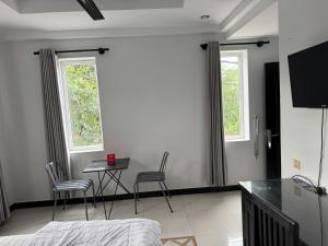 a bedroom with a table and chairs and two windows at Villa de Sancho in Phumĭ Réach Born (2)