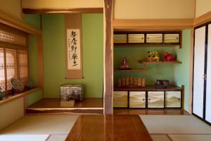 a room with green walls and a wooden table and shelves at 暮らしやaizu in Kitakata