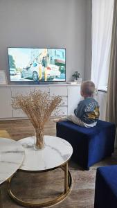 a little boy sitting on a chair in front of a tv at Golden Key 35m2 aprtament blisko Dworzec, Spodek, MCK, Self check-in, Parking in Katowice