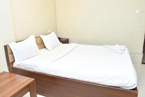 a bedroom with a bed with white sheets and a table at Raj Gharana in Raipur +2 photos