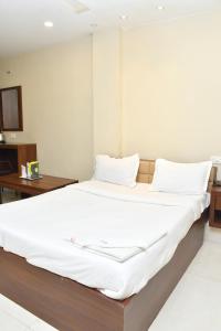 a bedroom with a large bed with white sheets at Raj Gharana in Raipur