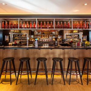 um bar com quatro bancos em frente a um balcão em citizenM Rotterdam em Roterdão