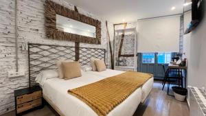a bedroom with a large white bed and a brick wall at Pensión Lo Bilbao in Bilbao
