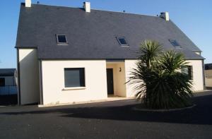 een wit huis met een grijs dak en een palmboom bij Villa Residence Kersaliou in Roscoff