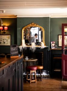 a man standing at a counter in a bar with a mirror at The Red Lion in Thames Ditton