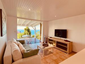 Μια τηλεόραση ή/και κέντρο ψυχαγωγίας στο Lodge Orchidée de la Villa La Palmira - Vue Mer Caraïbes - Jacuzzi Privé - Accès Piscine 5x9 - Lit King Size 180 - Climatisation - 4 étoiles - Proche commodités - TV connectée - Internet fibre - Proche Plage