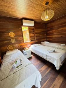 two beds in a room with wooden walls at Hotel e Restaurante Tribo Combú in Belém