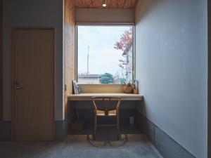 ein Fenster in einem Zimmer mit einem Tisch und einem Stuhl in der Unterkunft TABiE in Izumo