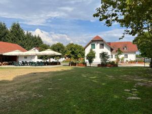 a yard with tables and umbrellas in front of a house at Kormorán Vendégház in Matty