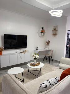 a white living room with a couch and a tv at Studio in Nanyuki with Mount Kenya Views in Nanyuki