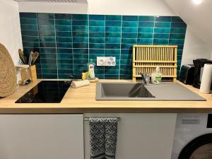 a kitchen with a sink and a blue tiled wall at Centre Nemours - Climatisation - Cosy Deluxe in Nemours
