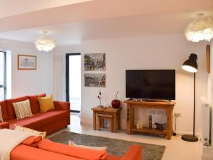 a living room with a red couch and a flat screen tv at Potters Pad in Alnwick