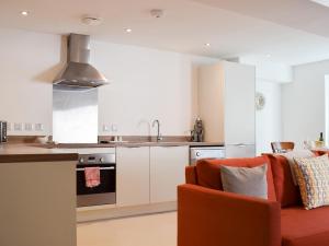 a kitchen with an orange couch in a living room at Potters Pad in Alnwick
