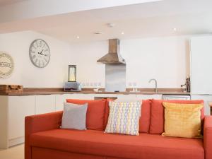 a orange couch in a kitchen with a clock on the wall at Potters Pad in Alnwick