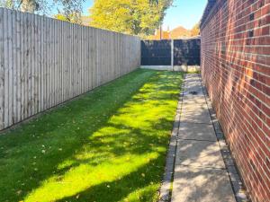 a backyard with a brick fence and a green lawn at Tilia Loft in Scotter