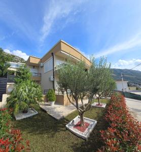 ein Haus mit zwei Bäumen davor in der Unterkunft Deluxe Apartmani Vila Pejovic Sutomore in Sutomore