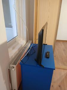 una tv appoggiata su un tavolo blu con un telecomando di Casa Avocaților a Corabia