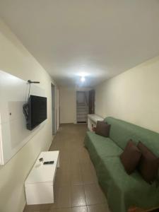 Una sala de estar con un sofá verde y un televisor. en Ao lado do Hospital Calixto excelente localização, en Itabuna