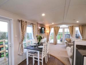 een keuken en woonkamer met een tafel en stoelen bij Rosefinch Cabin in Staintondale
