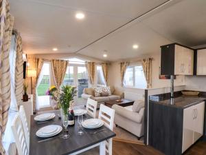 een keuken en woonkamer van een caravan met een tafel en stoelen bij Rosefinch Cabin in Staintondale