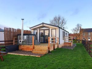 een klein huisje met een terras en een prieel bij Rosefinch Cabin in Staintondale