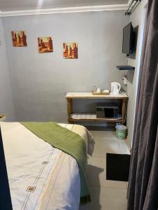 Thekiso Guest House في سنتوريون: غرفة بسرير وطاولة مع تلفزيون