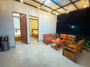 a living room with benches and a table and a bedroom at Fatmara Villa Full House in Kejajar