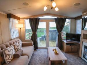 een woonkamer met een bank en een tv bij Swift Cabin in Staintondale