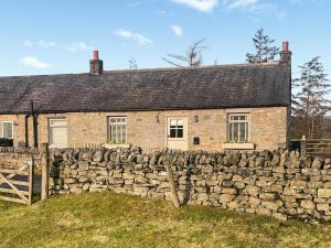 een oud stenen huis achter een stenen muur bij Night Sky Cottage in Kielder
