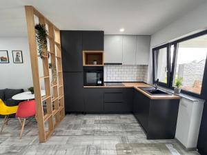 a kitchen with black cabinets and a table and a yellow chair at Popoveni Garden Vila in Craiova +9 photos