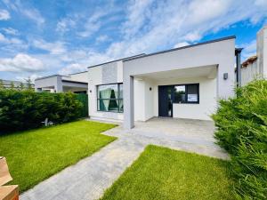 a white house with a green yard at Popoveni Garden Vila in Craiova