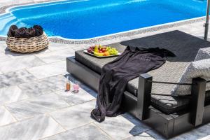 a bed next to a pool with a bowl of fruit at Aurora Mykonos Villas in Kalafatis