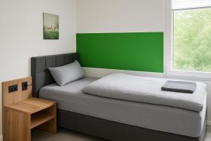 Livemore24 - Apartment 2 in Herten 24-7 Check-In في هيرتين: غرفة نوم مع سرير مع اللوح الأمامي الأخضر