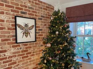 un albero di Natale con un'ape sopra accanto a un muro di mattoni di Sycamore Barn a Holt