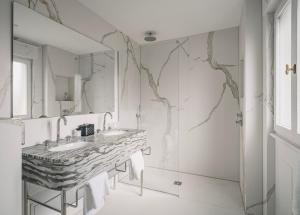 ein weißes Badezimmer mit Waschbecken und Spiegel in der Unterkunft Hôtel Régent Contades in Straßburg