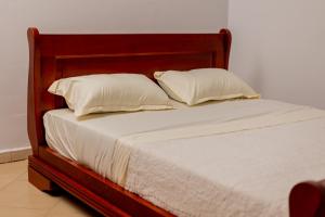 a bed with white sheets and pillows on it at Paradise Pathways Lweza in Kampala