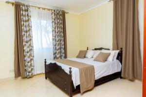 a bedroom with a bed and a large window at Luxury Homes and Apartments - Near Entebbe Airport in Kampala