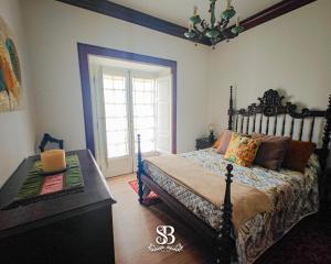 a bedroom with a bed and a table and a chandelier at Casa com Piscina Privada de 10m e Jardim, até 8 pessoas, perto do Porto in Landim