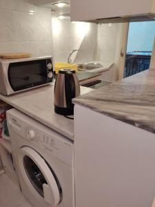 White Tower Cozy Studio OYR1 في سلانيك: مطبخ مع غسالة ملابس وميكروويف