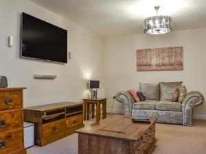 Song Bird Holiday Home في ويتبي: غرفة معيشة مع أريكة وتلفزيون