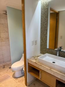 AULIFER Luxury Apartments في بلايا ديل كارمن: حمام مع حوض ومرحاض ومرآة +7 صور