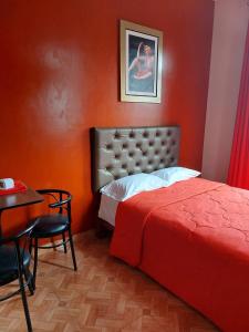 1 dormitorio con pared roja, cama y mesa en Anciejo inn ll, en Lima