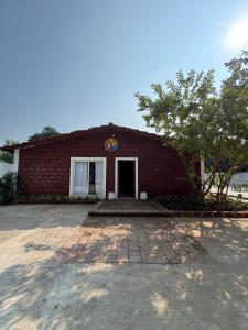 a red brick building with a tree in front of it at NOSSA GOA VILLA in MUMBAI GORAI in Mumbai