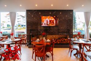 a dining room with tables and a fireplace at Augusta Centro Hotel in Canela