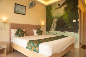 Nillara Kotagiri by Tropic Oasis Hotels في كوتاغيري: غرفة نوم بها سرير ولوحة على الحائط