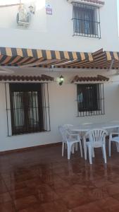 a white table and chairs in a room with windows at casa andaluza 109 in Novo Sancti Petri