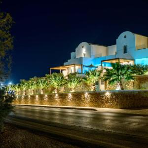 a building with a row of palm trees and lights at Safrani Suites in Fira